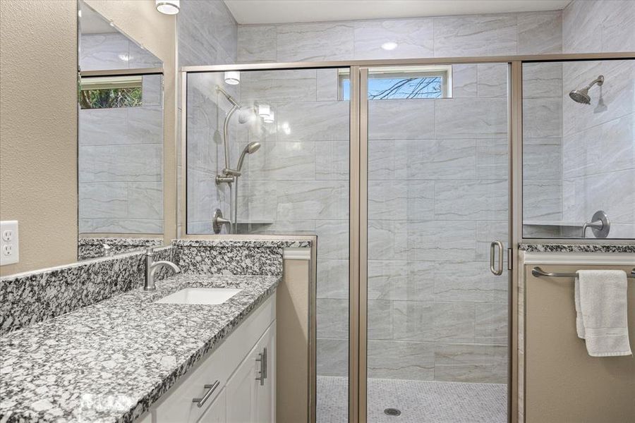 Bathroom featuring a stall shower, vanity, and healthy amount of natural light Bathroom featuring a stall shower, vanity, and healthy amount of natural light