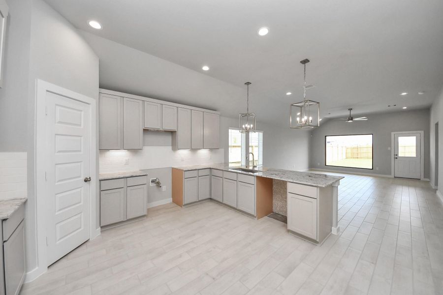 The kitchen is a culinary haven, featuring granite countertops, a tile backsplash, stainless steel appliances, 42” upper cabinets, and undercabinet lighting. Sample photo of completed home with similar floor plan. Actual colors and selections may vary.