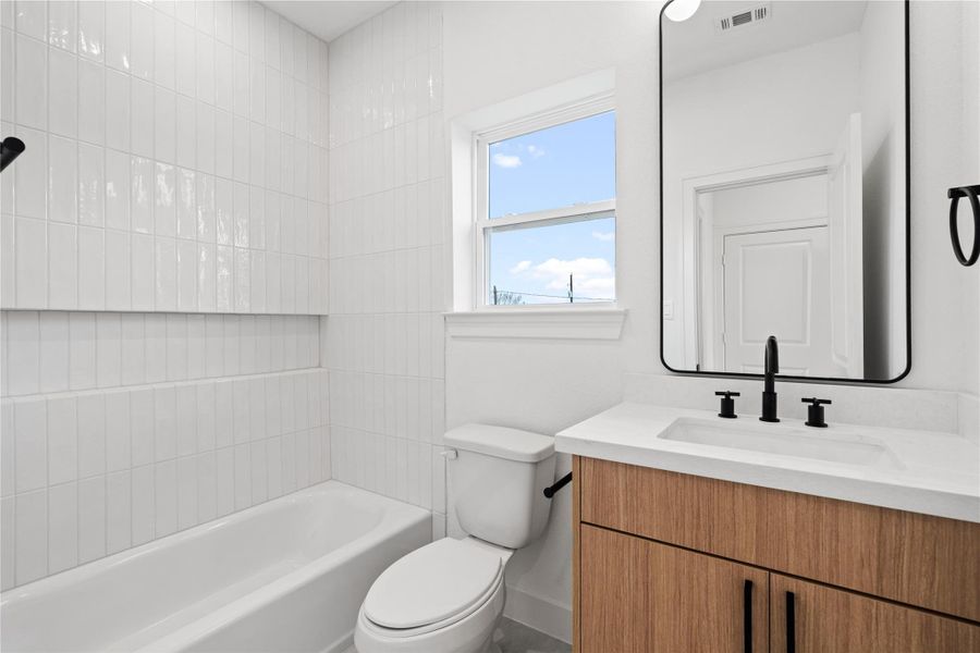 Secondary bathroom with a bright window, modern finishes, and a clean tiled tub surround.