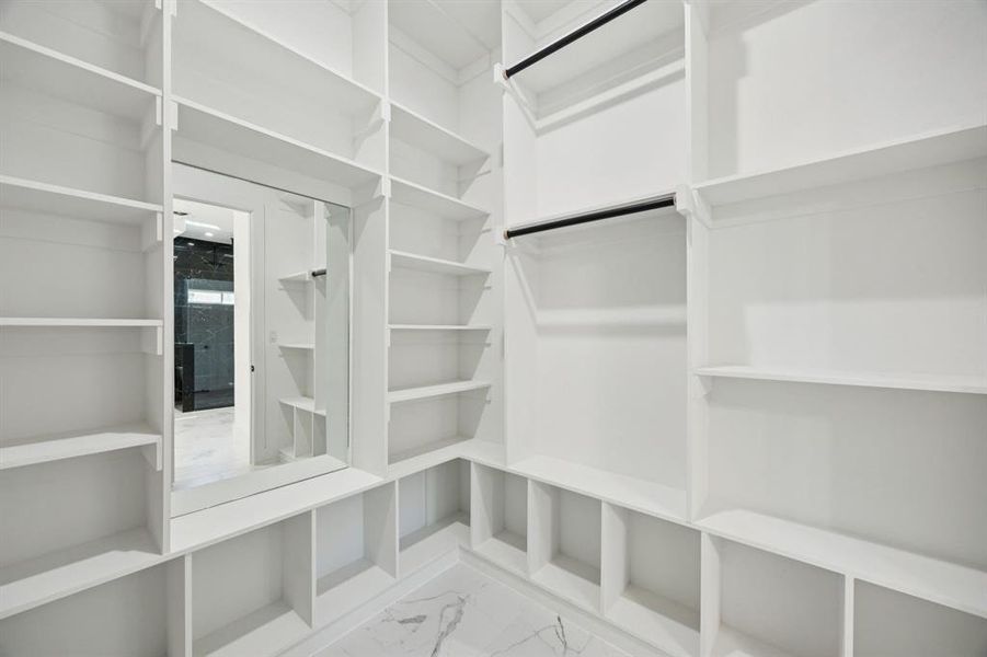 Spacious closet featuring light marble finish flooring