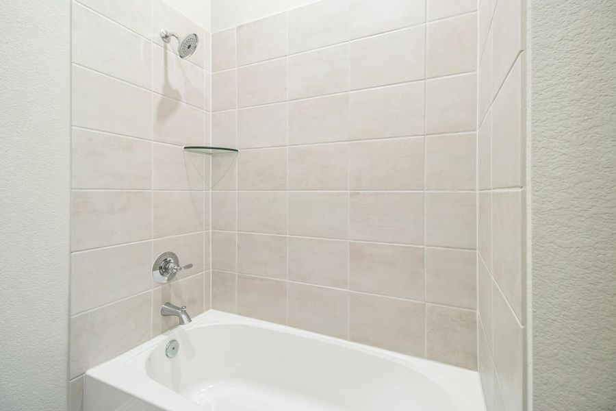 Bathroom featuring washtub / shower combination and a textured wall