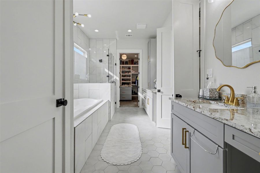 Primary bath featuring a walk in closet, a bath, a stall shower w/ bench,, dual vanity, and recessed lighting
