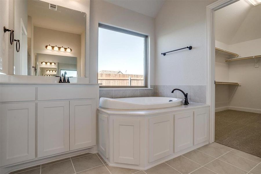 Bathroom with tile patterned flooring, vanity, a bathtub, and lofted ceiling