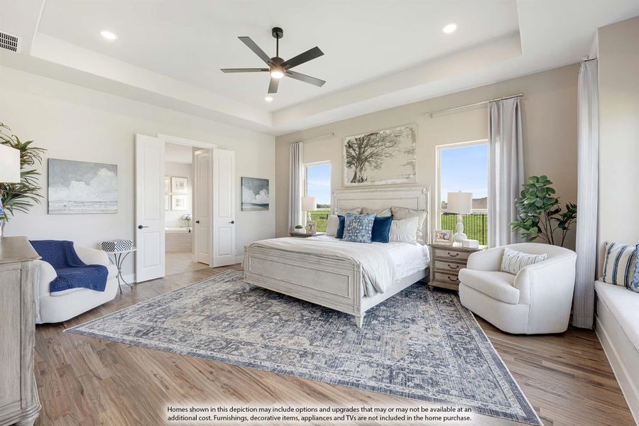 Master bedroom with tray ceiling, ceiling fan, hardwood floors, and ensuite bathroom access
