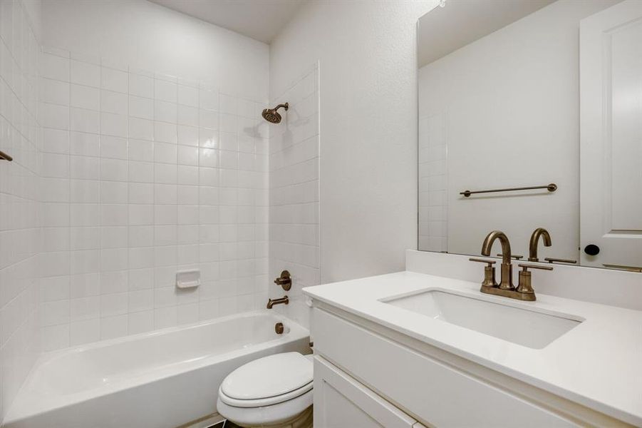 Bathroom featuring a built-in tub with white subway tile surround, a white vanity with integrated sink, and an expansive wall-mounted mirror