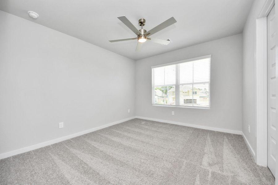 Secondary bedroom features plush carpeting, large windows that let in plenty of natural light, bright paint, and spacious closets. Sample photo of completed home with similar floor plan. Actual colors and selections may vary. Secondary bedroom features plush carpeting, large windows that let in plenty of natural light, bright paint, and spacious closets. Sample photo of completed home with similar floor plan. Actual colors and selections may vary.