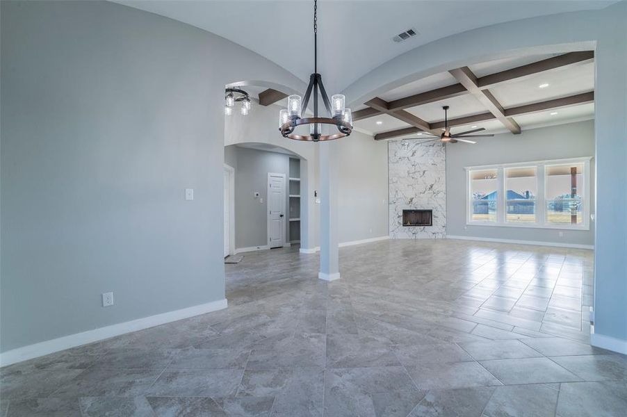 Unfurnished living room featuring coffered ceiling, a ceiling fan, a fireplace, beam ceiling, and a chandelier Unfurnished living room featuring coffered ceiling, a ceiling fan, a fireplace, beam ceiling, and a chandelier