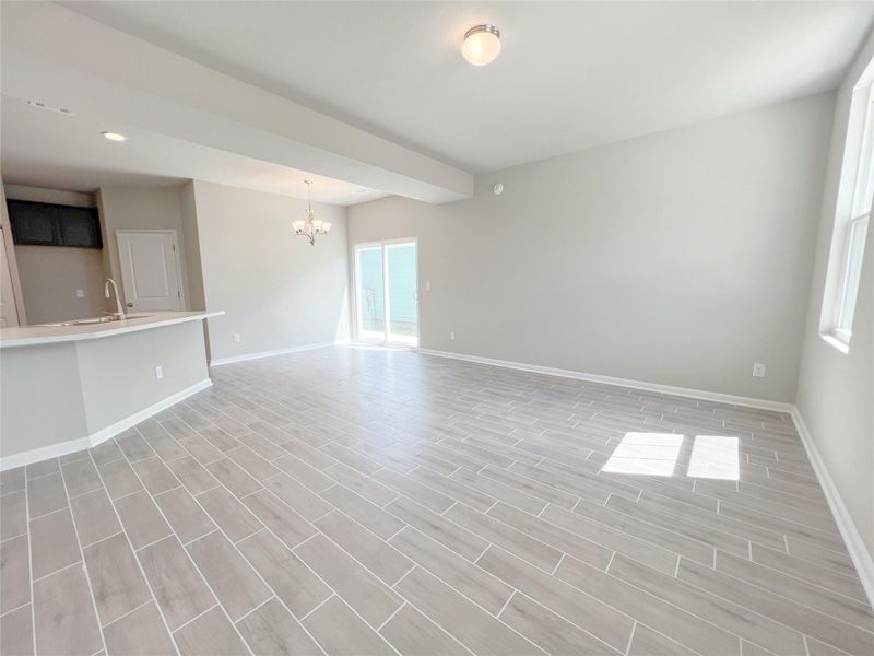 Unfurnished living room featuring wood tiled floors, a chandelier, and plenty of natural light