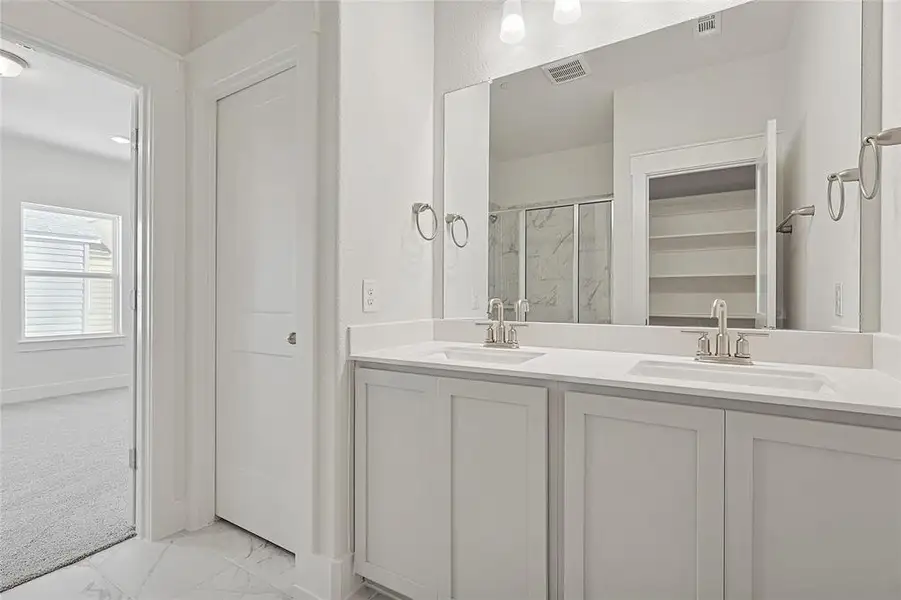 Bathroom featuring a dual vanity with undermount sinks, a large mirror, and tiled flooring