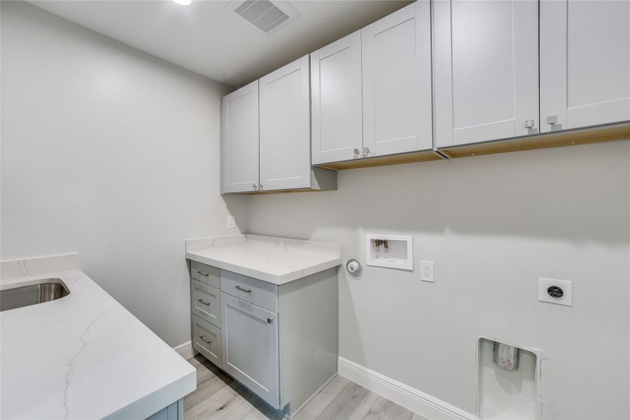 Washroom with washer hookup, cabinets, light hardwood / wood-style flooring, and hookup for an electric dryer