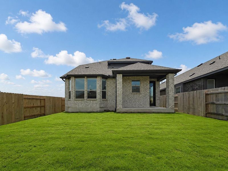 A fenced yard provides privacy and a verdant backdrop to this home's brick exterior and covered patio.