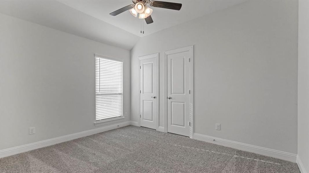 Unfurnished bedroom featuring lofted ceiling, carpet floors, and a ceiling fan