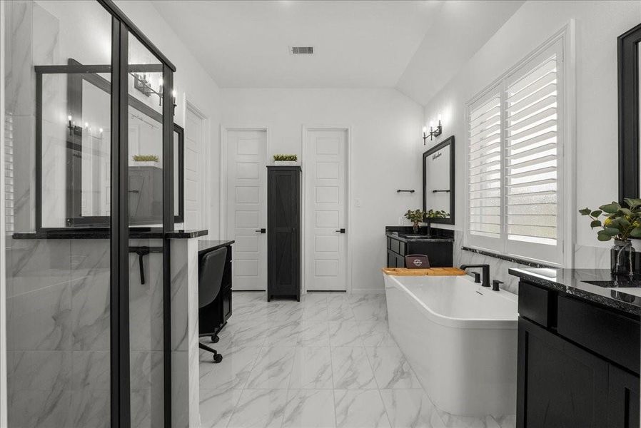 The luxurious primary en-suite bath features dual vanities, a walk-in shower, soaking tub, and separate his-and-her walk-in closets.