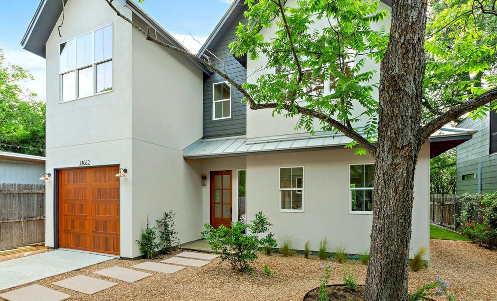 View of front facade featuring fence, a standing seam roof, a garage, and stucco siding