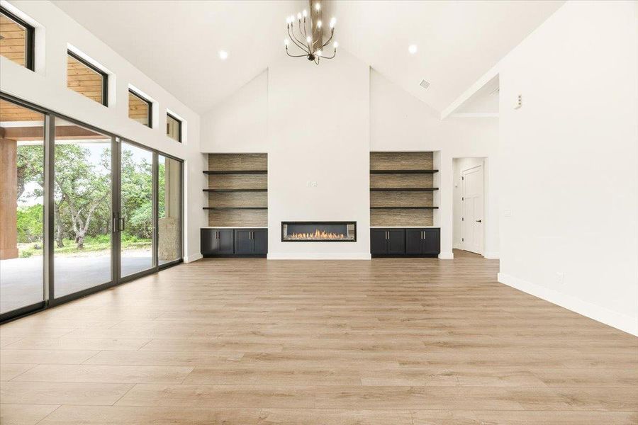 Vast sliding glass doors connect an airy living area with soaring ceilings and a contemporary fireplace to the natural landscape.