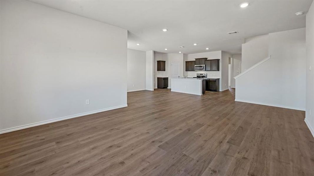 Open-concept living space featuring wood-finish flooring, recessed lighting, and a white baseboard trim