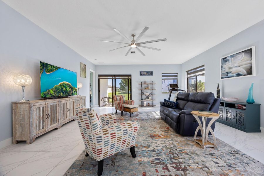 Living area featuring light marble finish flooring, plenty of natural light, and a ceiling fan