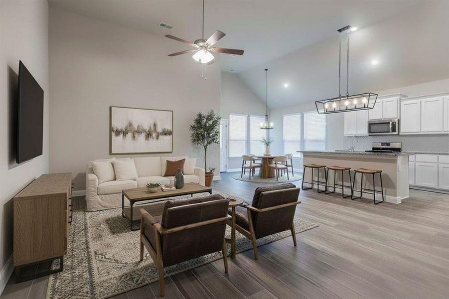 Living room featuring high vaulted ceiling, a chandelier, light wood-style flooring, and ceiling fan Living room featuring high vaulted ceiling, a chandelier, light wood-style flooring, and ceiling fan