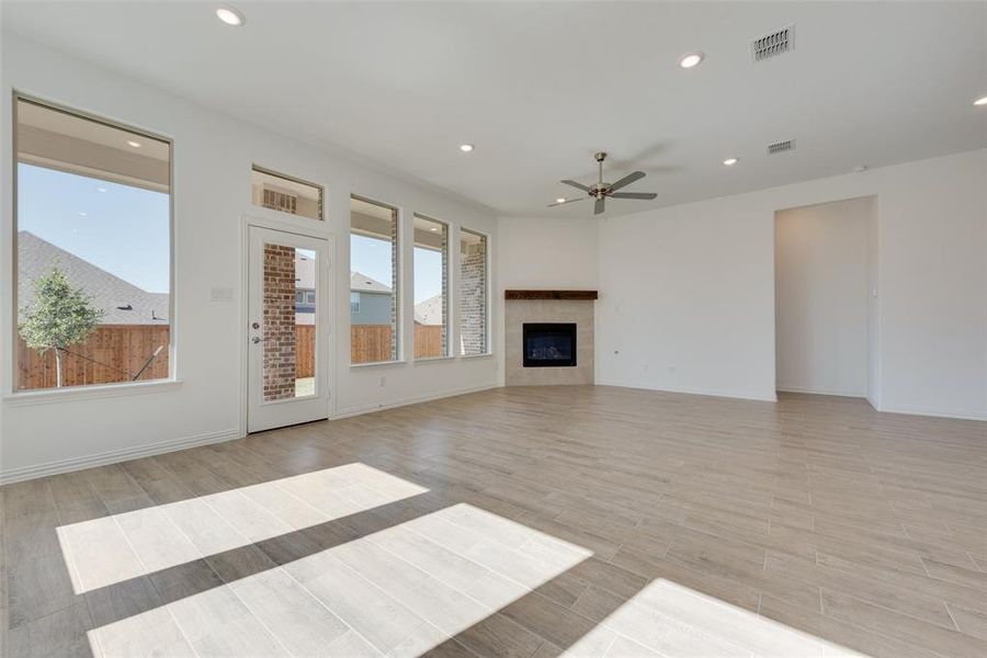 Unfurnished living room with ceiling fan, light hardwood / wood-style floors, and a high end fireplace