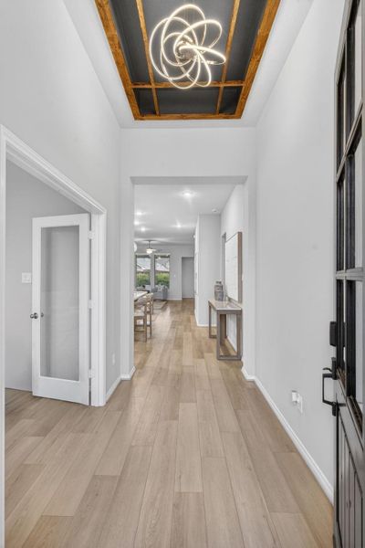 This photo showcases a bright, modern hallway with a striking ceiling light fixture. The space is open and inviting, leading to a living area on this beautiful home. This photo showcases a bright, modern hallway with a striking ceiling light fixture. The space is open and inviting, leading to a living area on this beautiful home.
