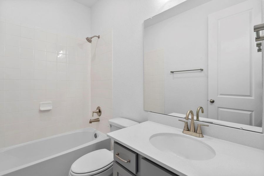 The secondary bath features tile flooring, custom stained cabinetry and light countertops and a shower/tub combo. Perfect for accommodating any visiting family and friends.