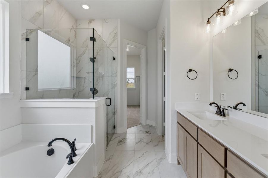 Bathroom featuring a tile floor, a shower with a clear glass enclosure, a built-in bathtub with a dark-finish faucet, and a double vanity with a light-finish cabinet, white countertops, and dark-finish fixtures