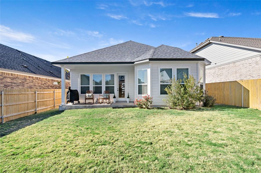 Back of property featuring a fenced backyard, roof with shingles, and a patio