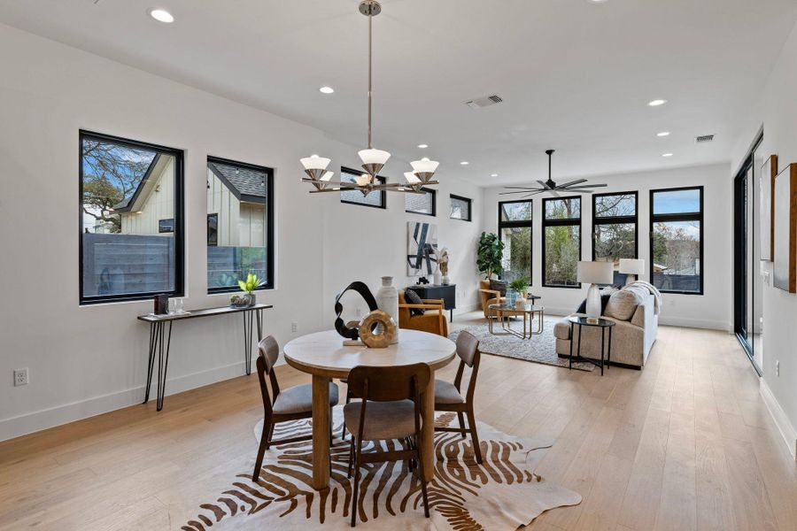 Dining space with recessed lighting, light wood finished floors, baseboards, a ceiling fan, and a chandelier