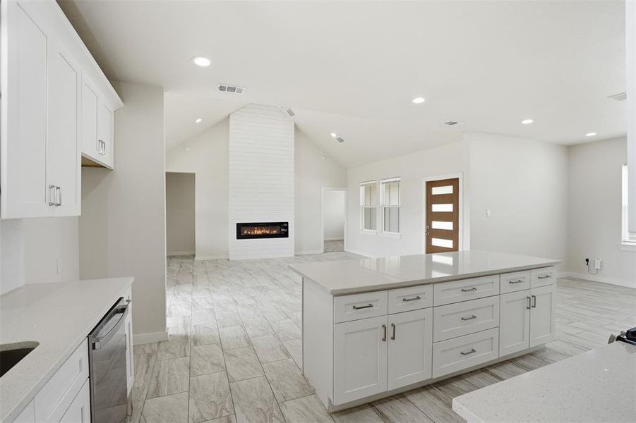 Open-concept living space featuring a vaulted ceiling and an electric fireplace with a shiplap surround