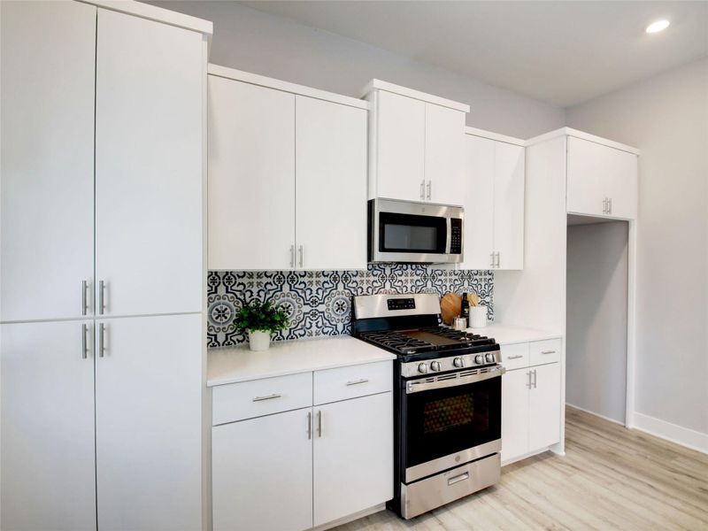 Kitchen featuring stainless steel appliances, white cabinetry, and light wood-style floors