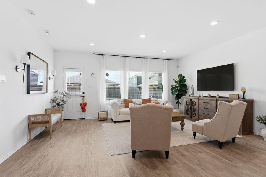 Bright open-concept living area with abundant natural light and warm vinyl wood flooring. Bright open-concept living area with abundant natural light and warm vinyl wood flooring.