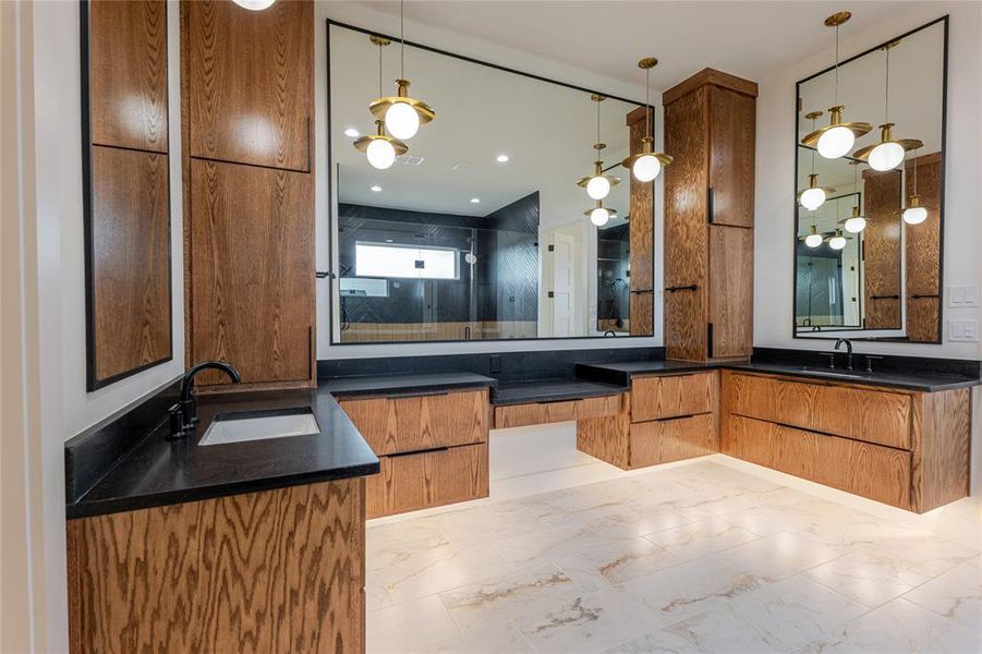Full bathroom with light marble finish flooring, a shower stall, and two vanities