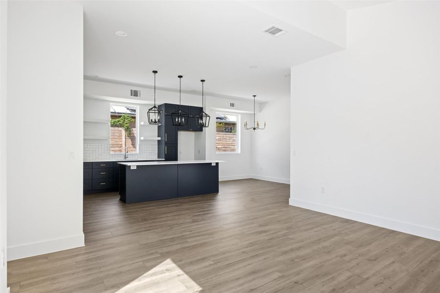 Kitchen featuring hanging light fixtures, dark cabinetry, tasteful backsplash, light countertops, and recessed lighting Kitchen featuring hanging light fixtures, dark cabinetry, tasteful backsplash, light countertops, and recessed lighting
