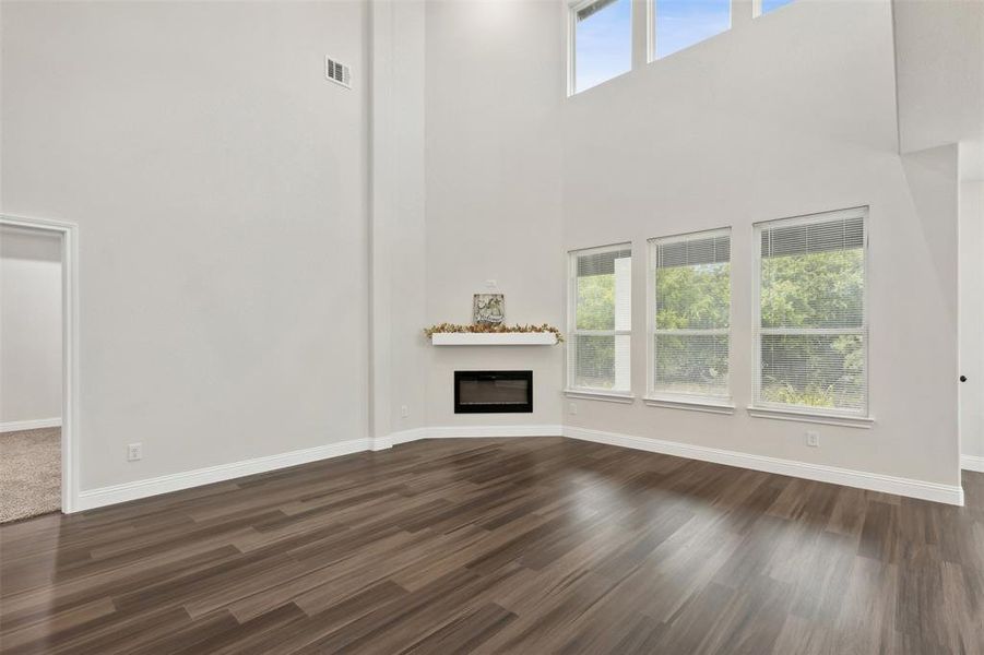 Unfurnished living room with a high ceiling and dark hardwood / wood-style floors