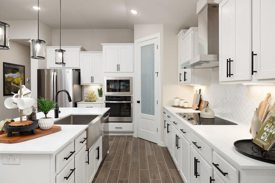 White cabinetry and warm wood flooring define this contemporary kitchen, offering both style and utility.