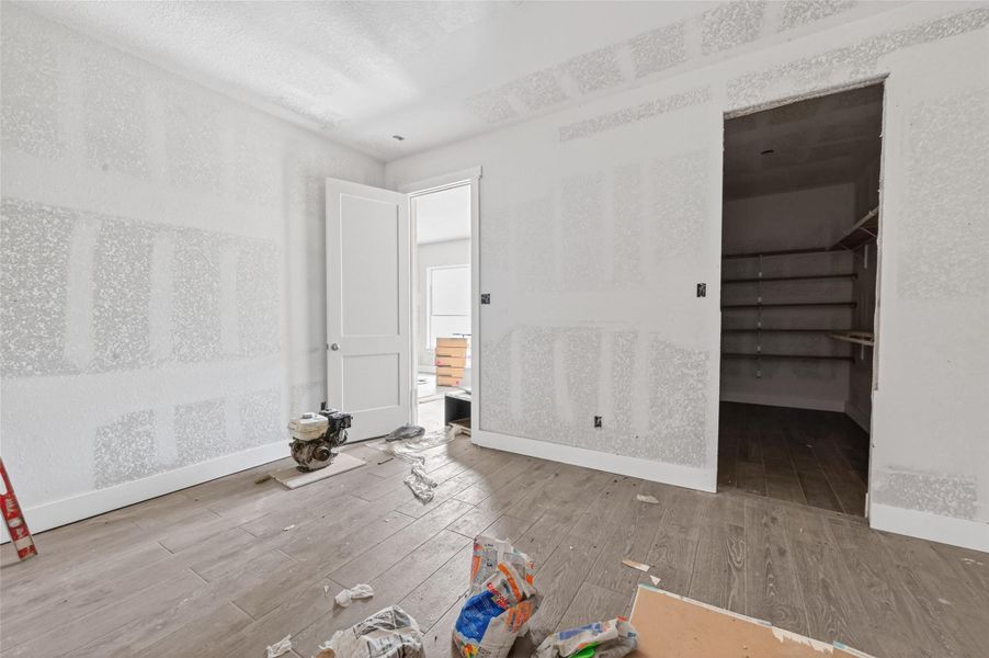 Main-level interior under construction with unfinished drywall, and adjacent storage area