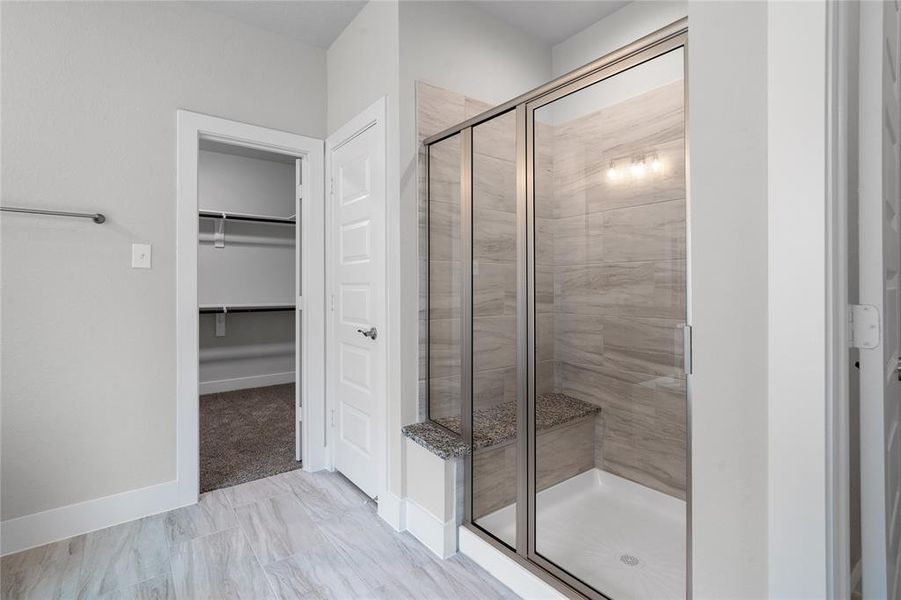 This primary bathroom is definitely move-in ready! Featuring a framed walk-in shower with tile surround, separate garden tub for soaking after a long day with custom tile detailing, grey cabinets with light countertops, spacious walk-in closet with shelving, high ceilings, custom paint, sleek and modern finishes.