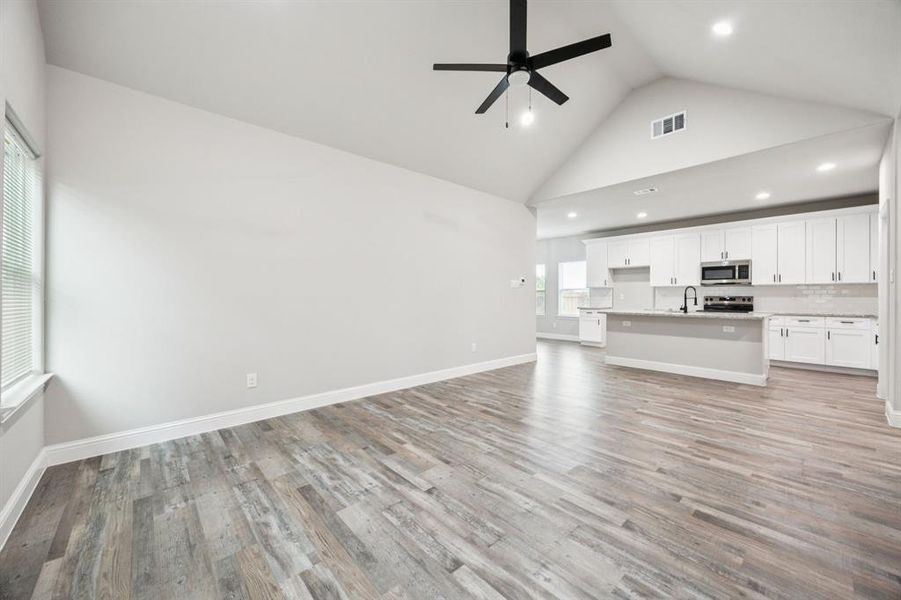 Unfurnished living room featuring high vaulted ceiling, light wood-style floors, recessed lighting, and a ceiling fan