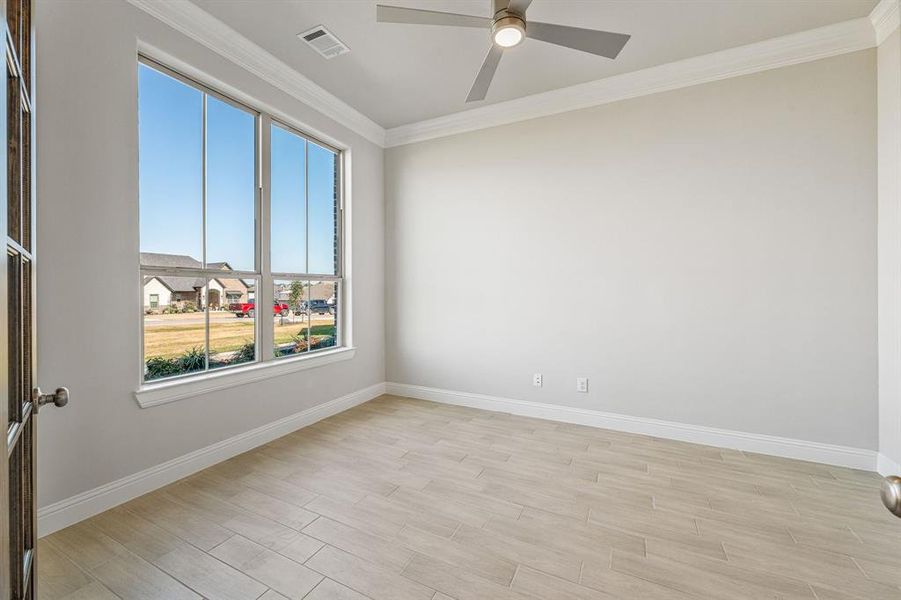 Empty room featuring ornamental molding, wood tiled floors, a residential view, and a ceiling fan