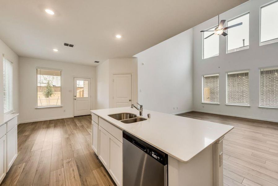 Kitchen featuring light wood-type flooring, white cabinetry, dishwasher, an island with sink, and sink