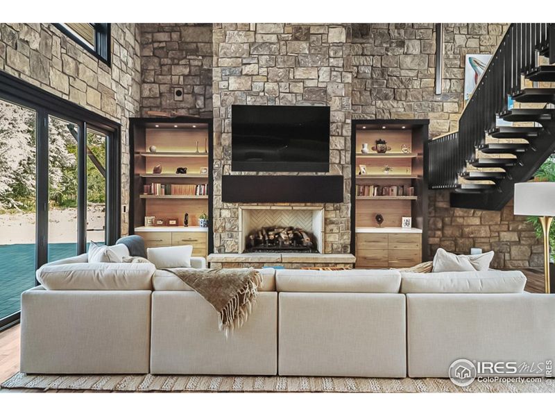 Great room with custom bookshelves, masonry fireplace and natural stone walls