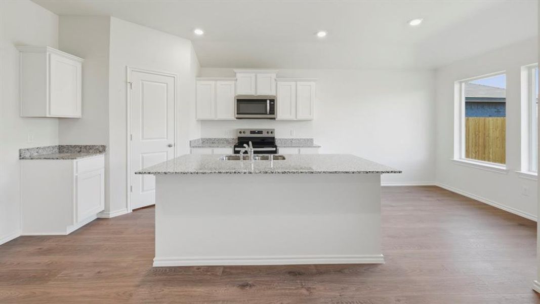 Kitchen featuring white cabinets, light stone counters, stainless steel appliances, a center island with sink, and recessed lighting Kitchen featuring white cabinets, light stone counters, stainless steel appliances, a center island with sink, and recessed lighting