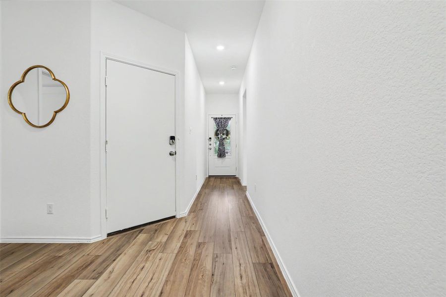 Hallway with wood-finish flooring, white walls, and recessed lighting