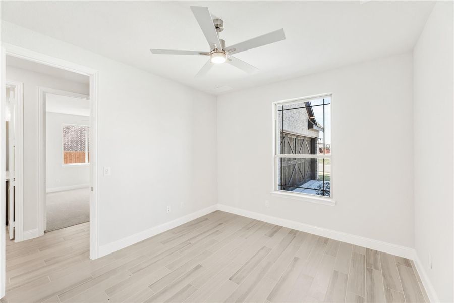 Empty bedroom with light wood floors, ceiling fan, and single window with outdoor view Empty bedroom with light wood floors, ceiling fan, and single window with outdoor view