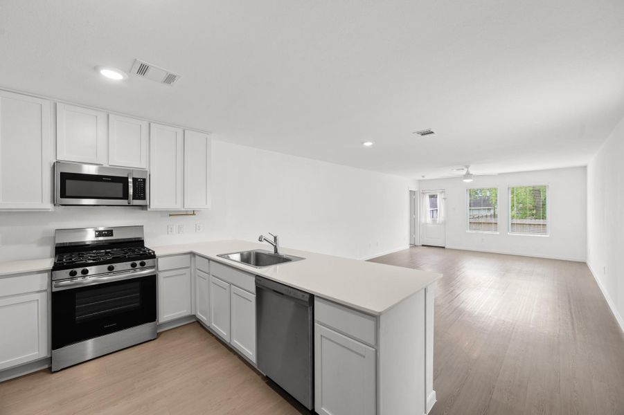 Open-concept kitchen flows directly into the living area, with a spacious peninsula creating a natural connection between the two spaces. Stainless steel appliances, white cabinetry, and recessed lighting provide a clean, contemporary look. Open-concept kitchen flows directly into the living area, with a spacious peninsula creating a natural connection between the two spaces. Stainless steel appliances, white cabinetry, and recessed lighting provide a clean, contemporary look.
