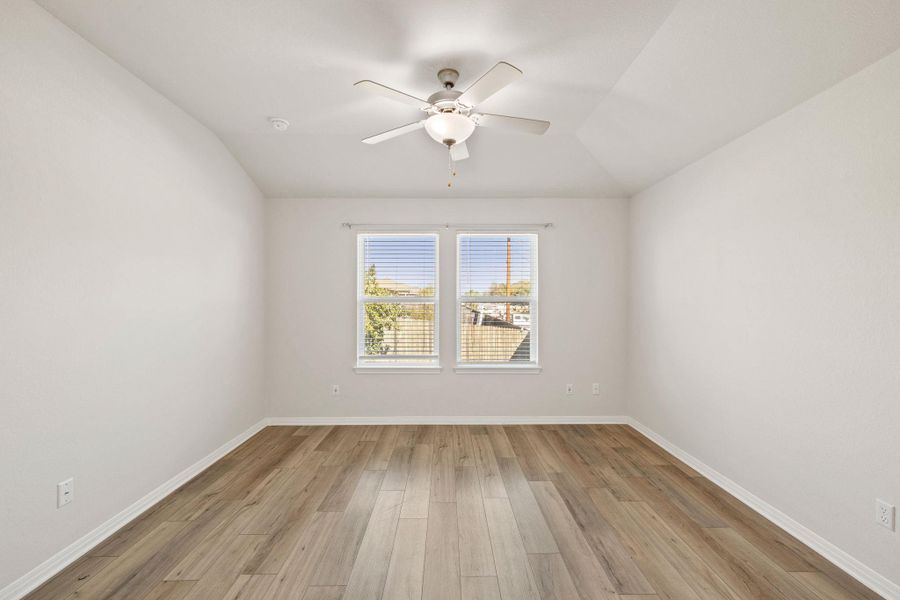 Spare room featuring light wood finished floors, vaulted ceiling, and a ceiling fan Spare room featuring light wood finished floors, vaulted ceiling, and a ceiling fan