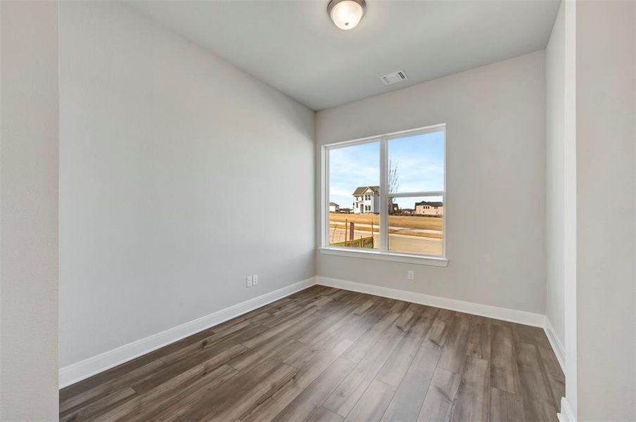 Spare room featuring dark wood-style floors and baseboards