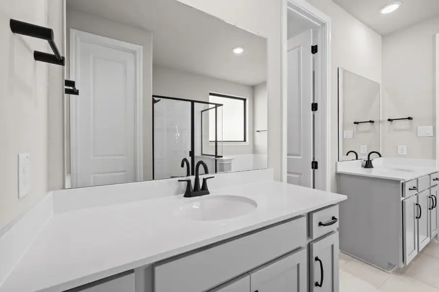 The en-suite bathroom offers a spa-like atmosphere with its elegant design, high end finishes, and tasteful lighting, creating a retreat within your own home.