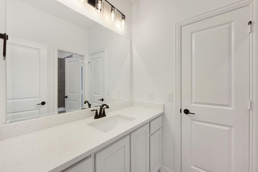 Bathroom vanity with white quartz countertop, single sink, dark faucet, large mirror, and pendant lights above. Bathroom vanity with white quartz countertop, single sink, dark faucet, large mirror, and pendant lights above.
