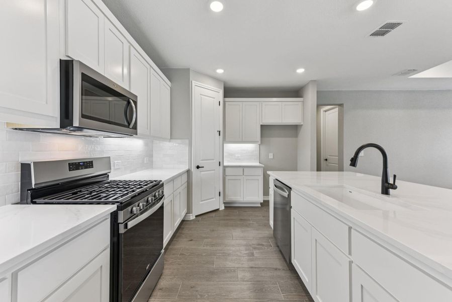 Kitchen with appliances with stainless steel finishes, tasteful backsplash, recessed lighting, light stone counters, and white cabinets Kitchen with appliances with stainless steel finishes, tasteful backsplash, recessed lighting, light stone counters, and white cabinets